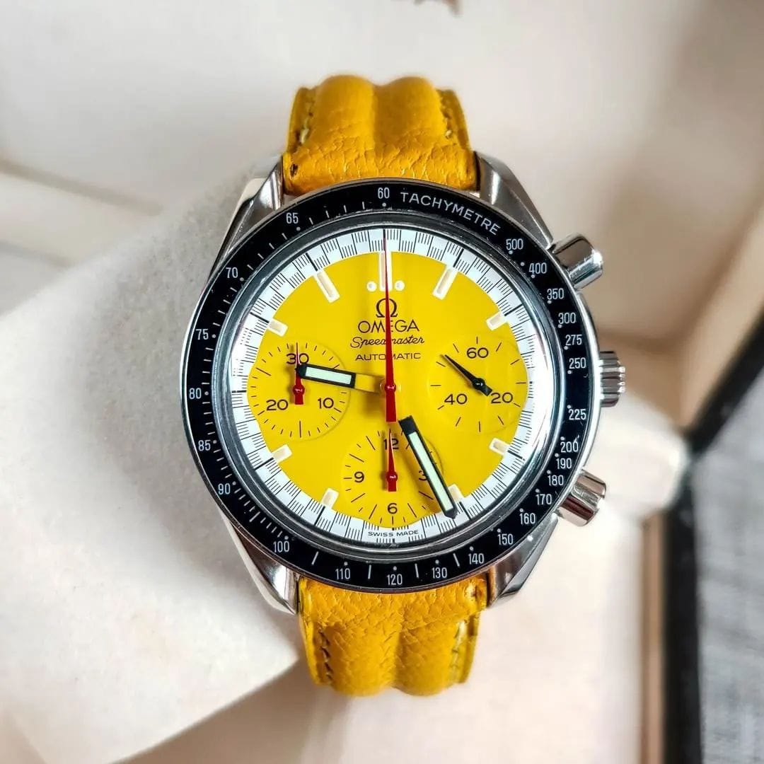 Schumacher yellow dial. Outer ring along the seconds track in a black-and-white “racing” pattern. Chronograph hands in red. Hour, minute and seconds hand in black. Omega Speedmaster Reduced 3510.12.00