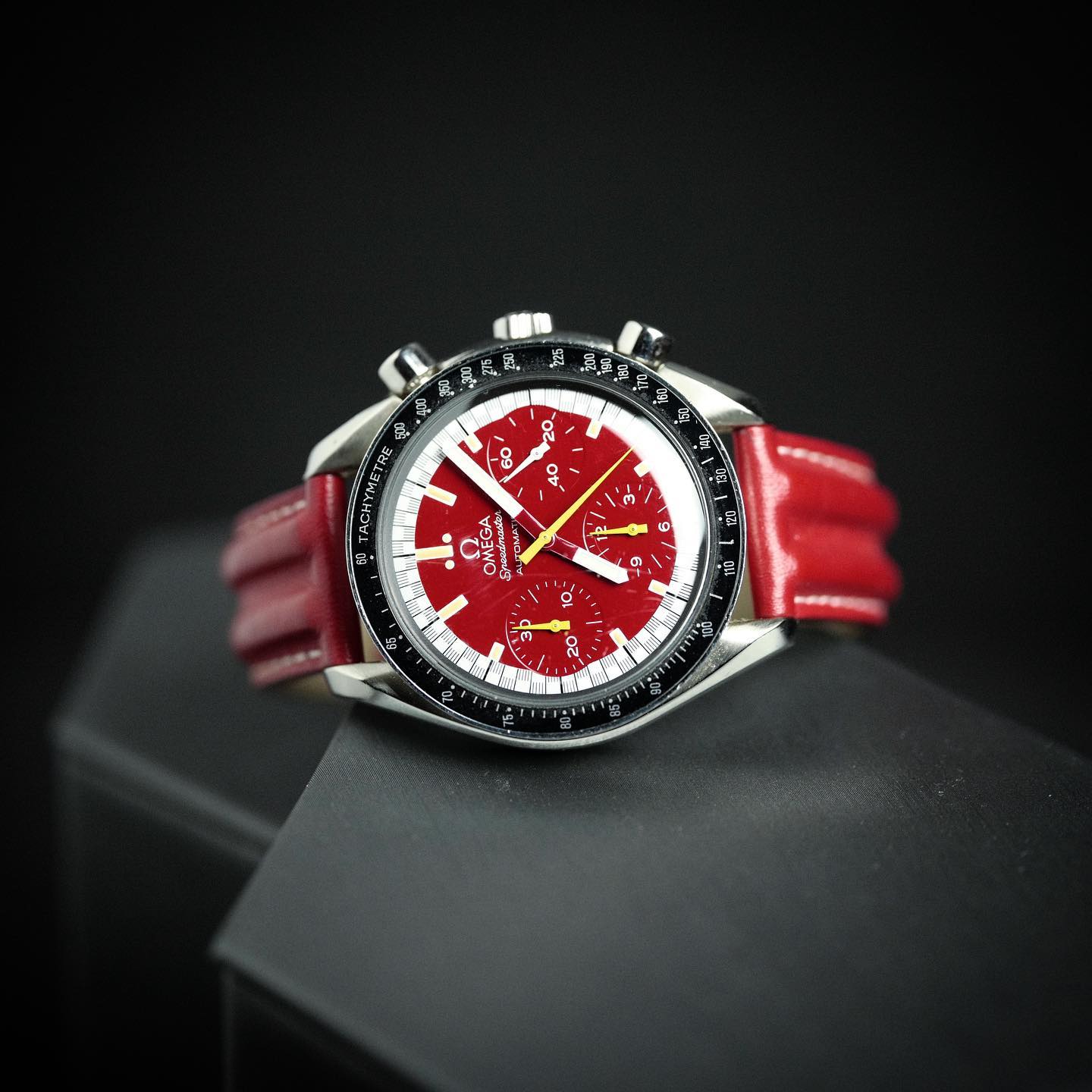 Schumacher red dial (Ferrari). Outer ring along the seconds track in a black-and-white “racing” pattern. Chronograph hands in yellow. Hour, minute and seconds hand in white. Omega Speedmaster Reduced 3810.61.41