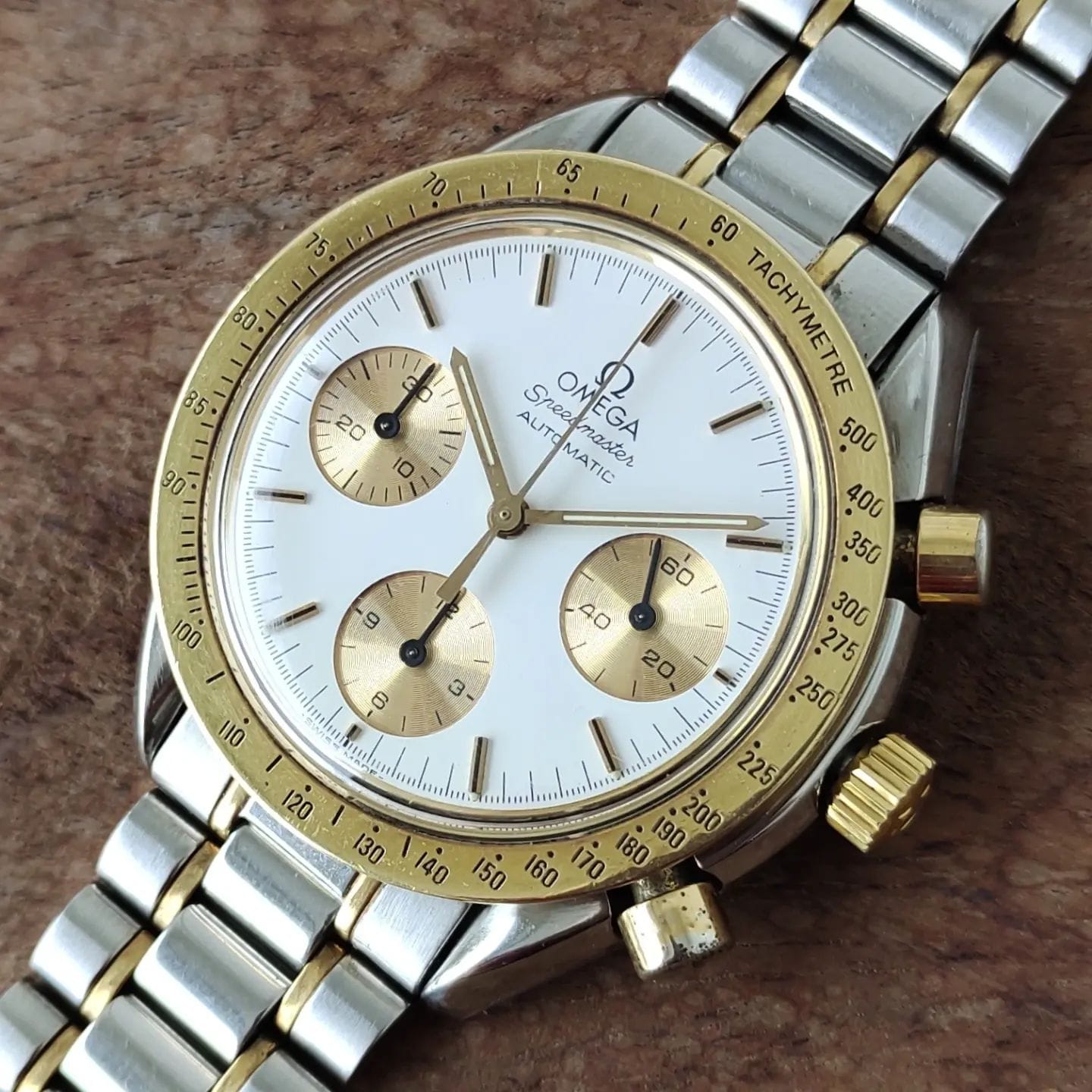 White dial with golden bezel. Gold minute counter and chronograph subdials. Golden applied indices and hands. Omega Speedmaster Reduced DA 175.0033
