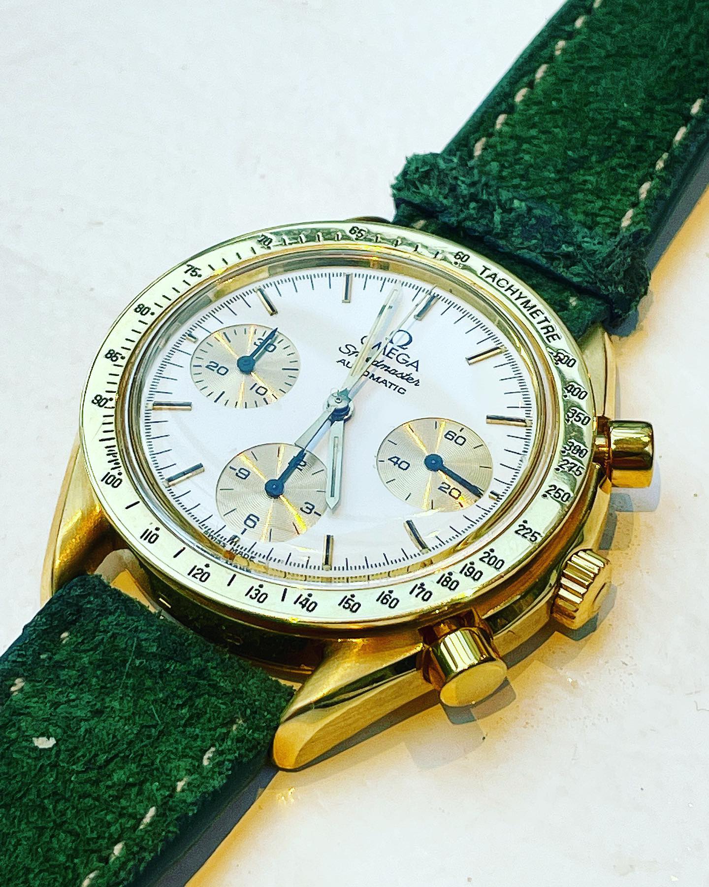 White dial with golden bezel and a black tachymètre inlay. Gold minute counter and chronograph subdials.Golden applied indices. Gold minute, hour and chronograph seconds hand. Subdials with black hands. Omega Speedmaster Reduced Unclear
