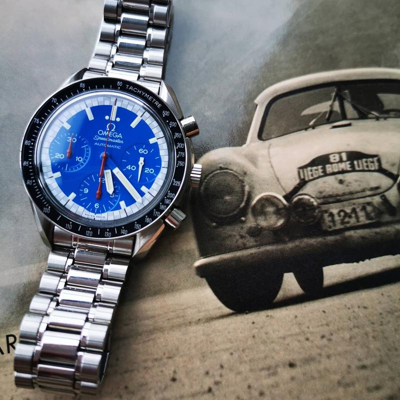 Schumacher blue dial. Outer ring along the seconds track in a black-and-white “racing” pattern. Chronograph hands in red. Hour, minute and seconds hand in white. Omega Speedmaster Reduced 3510.81.00